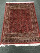 A Persian Bokhara rug on red ground,