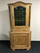 A blonde oak corner cabinet