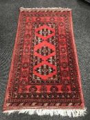 A Persian fringed woollen rug on red ground