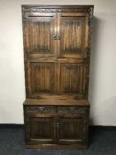 A carved oak linen fold bureau fitted cupboards above and below