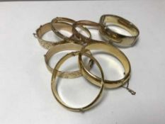 A collection of seven 9ct gold metal core bangles, one gold on silver.