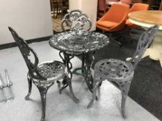 A circular metal garden table and three chairs