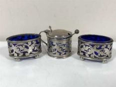 A silver three piece cruet set with blue glass liners and caddy spoon