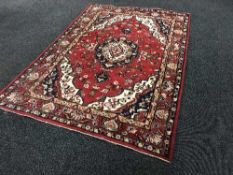 A fringed woollen Heriz rug on red ground