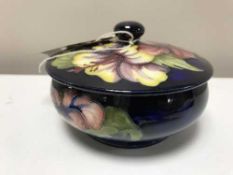 A Moorcroft lidded bowl, dark blue decorated with flowers,