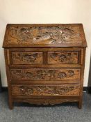 A carved oak writing bureau with oriental decoration, fitted with four drawers below, width 92 cm.