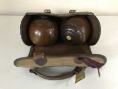 A bowls bag containing two vintage wooden balls