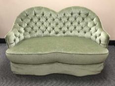 A shaped green button dralon two seater settee