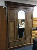 An antique inlaid mahogany mirror door wardrobe