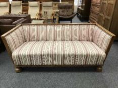 An early 20th century oak framed settee in striped fabric
