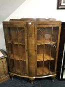 A shaped walnut display cabinet