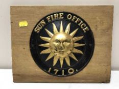A tin Sun Fire office insurance plaque mounted on pine board