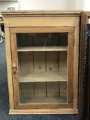 An antique striped pine glazed door wall cabinet