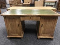 A pine twin pedestal desk with green tooled leather top