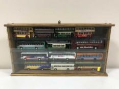 A display case of fourteen die cast buses and trams