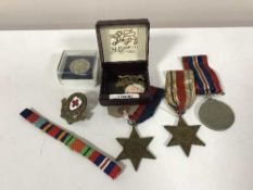 A trio of WWII medals with ribbons and military badges