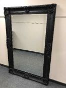 A black ornate mirror with bevelled glass, 120cm by 185cm.