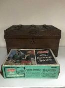 A boxed Coleman camp stove, tin trunk of board games,