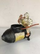 A cast metal Michelin man seated on a compressor