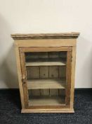 An antique striped pine glazed door wall cabinet