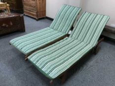 A pair of adjustable teak sun beds with cushions
