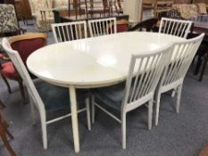 A white extending dining table with two leaves and six chairs