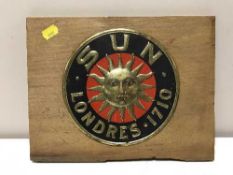 A Sun Londers insurance plaque mounted on a pine board