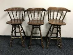 A set of three revolving pub bar stools with brass foot rails