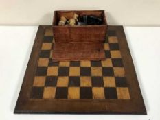 An early 20th century chess board and a pine box of chess pieces