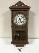 A carved oak cased wall clock with pendulum and key