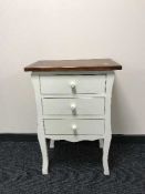 A white three drawer bedside chest with pine top