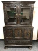 An eighteenth century carved oak coffer with glazed cupboard above,