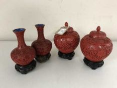 A pair of cinnabar vases on wooden stands,