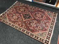 A fringed Persian rug of geometric design on red ground