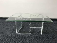 A glass topped ghost coffee table on perspex bases
