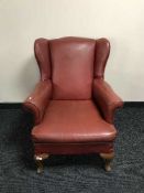 A red vinyl upholstered wingback armchair on Queen Anne style legs