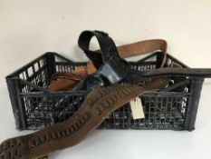 A basket of assorted leather ammunition belts, knife and gun holsters,