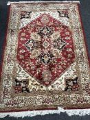 A fringed Persian Heriz rug on red ground 190 cm x 140 cm