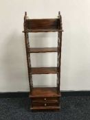 A set of narrow mahogany open bookshelves fitted with drawers