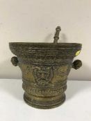 A large embossed brass pestle and mortar