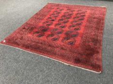 A large woollen fringed Afghan carpet on red ground