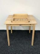 A square teak garden table and two drinks trays