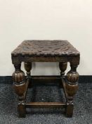 An early twentieth century carved oak leather upholstered footstool