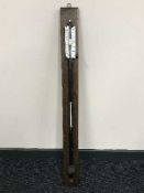 A lacquered metal ship's barometer on oak panel
