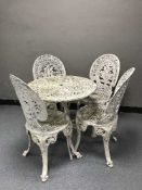 A circular cast metal garden table with four chairs