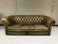 A tan leather Chesterfield style buttoned three seater settee