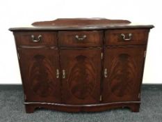 An inlaid mahogany serpentine fronted triple door sideboard