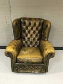 A tan leather Chesterfield style buttoned armchair