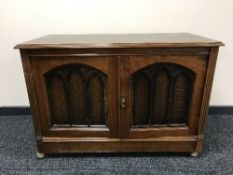 An oak two door cabinet, an oak tapestry fire screen,