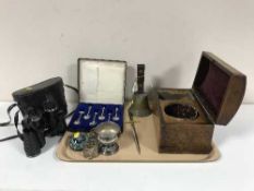 A tray of brass hand bell, glass paperweight, plated napkin rings, cased silver jubilee tea spoons,